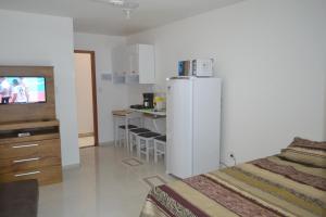 a room with a bed and a kitchen with a refrigerator at Loft Centro in Arraial do Cabo