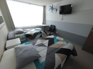 a bedroom with two beds and a tv on the wall at Fragata Camaná in Camaná