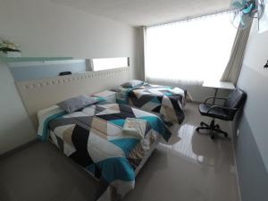 a bedroom with two beds and a chair and a window at Fragata Camaná in Camaná +51 photos