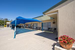 a blue umbrella in a parking lot next to a building at Caboolture Motel in Caboolture