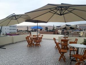 a group of tables and chairs with umbrellas on a roof at Residencial Mamamia in Tacna
