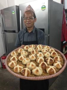 
a man holding a tray full of doughnuts at Tiger Mountain Pokhara Lodge in Pokhara
