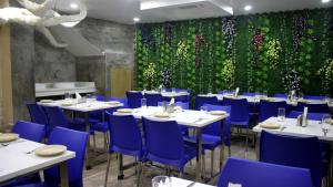 a restaurant with white tables and blue chairs and a green wall at Hotel Shreemoyee Inn - Kamakhya Temple in Guwahati