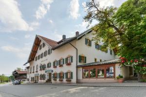 ein großes weißes Gebäude mit grünen Fensterläden in der Unterkunft Posthotel Hofherr in Königsdorf