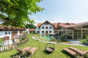 eine Außenansicht eines Hauses mit einem Garten mit Liegestühlen in der Unterkunft Posthotel Hofherr in Königsdorf