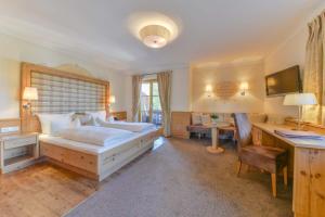 ein Schlafzimmer mit einem Bett und einem Schreibtisch mit einem Computer in der Unterkunft Posthotel Hofherr in Königsdorf