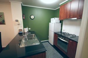- une cuisine avec des murs verts, un évier et un réfrigérateur dans l'établissement CityPoint - Melbourne, à Melbourne
