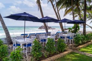 a group of chairs and umbrellas on the beach at Rockside Cabanas Hotel in Unawatuna