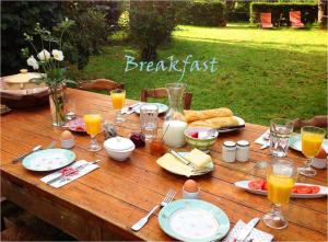 a wooden table with food and glasses of orange juice at Domaine Charente Glamping Familyroom Le Jardin with external toilet & shower house & outdoor kitchen in Mazières