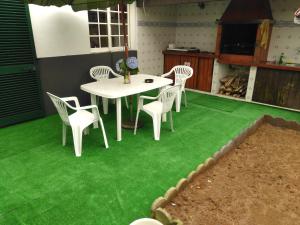 ポンタ・デルガダにあるPedro Sousa Rooms na Relvaの緑の芝生の上にテーブルと椅子が備わるパティオ