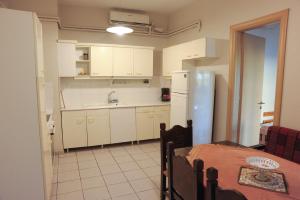 a kitchen with white cabinets and a table and a refrigerator at Spyrou Studios & Apartments in Platanidia