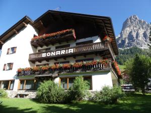 a building with flowers on the balconies in front of a mountain at Garni Bonaria in Corvara in Badia