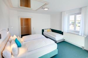 a white bedroom with two beds and a window at Hotel Kleiner König in Schwangau