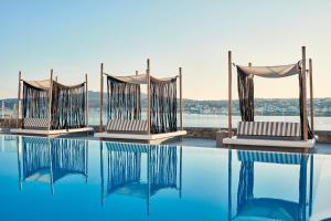 una piscina con sillas y vistas al agua en Mykonos No5 Luxury Suites & Villas, en Ornos