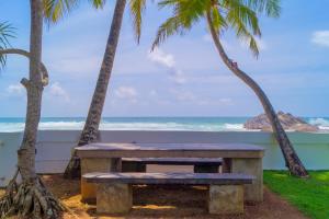 a picnic table on the beach with palm trees at Rockside Cabanas Hotel in Unawatuna