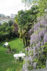 einen Tisch und Stühle in einem Garten mit lila Blumen in der Unterkunft Villa Dampierre in Pau