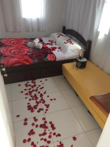 a bedroom with a bed with red flowers on the floor at Suítes da Erô in Arraial do Cabo