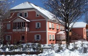 una gran casa roja con nieve delante en Residenze Sonnenschein Casa Rosa, en Villabassa