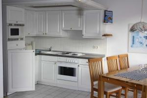 een keuken met witte kasten en een tafel met stoelen bij Fewo Sommergarten 4002_LUCI in Ostseebad Karlshagen