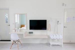 ein weißes Wohnzimmer mit einem TV an der Wand in der Unterkunft Let's Go Papa in Taitung