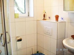 a white tiled bathroom with a sink and a shower at FH Charlottchen_WEIG in Ostseebad Karlshagen