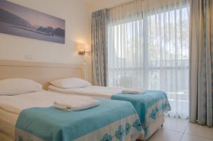Habitación de hotel con 2 camas y ventana en Regina Goren Hotel, en Ashkelon