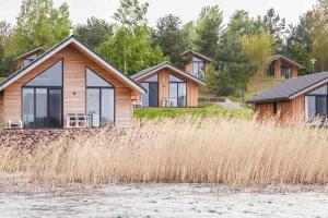 a house on the shore of a lake with tall grass at See- und Waldresort Gröbern in Gröbern