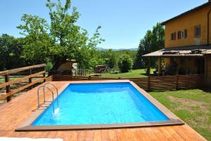 een groot zwembad op een houten terras met een huis bij Appartamento Lux in Pasturana
