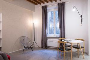 ein Wohnzimmer mit einem Tisch, Stühlen und einem Fenster in der Unterkunft Terme 53 in Siena