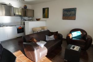 a living room with a leather couch and a kitchen at Port Mezua in Mèze