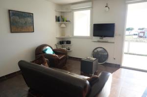 a living room with a couch and a tv at Port Mezua in Mèze