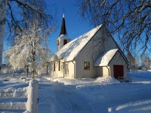 a white church with a steeple in the snow at Kjølen Hotel Trysil in Trysil