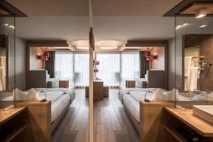 Habitación de hotel con 2 camas y espejo en Das Panorama Designhotel en Caldaro