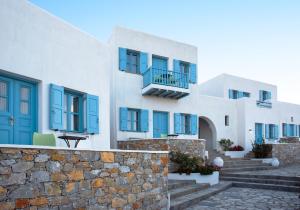 ein Gebäude mit blauen Fenstern und einer Steinmauer in der Unterkunft Aeri in Folegandros Chora