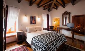 a bedroom with a bed and a desk and a television at Archontiko Soulioti in Ayiá