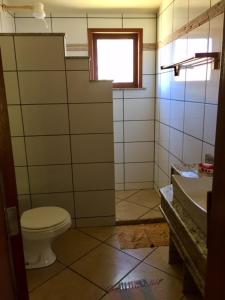 a bathroom with a toilet and a sink and a window at Bahiadomizil in Canavieiras