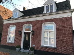 een rood bakstenen huis met een zwarte deur bij Zzzuite25 in Oosterhout
