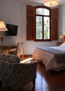 a bedroom with a bed and a chair and a tv at Hotel Casablanca Koeler in Petrópolis