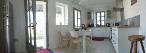 ル・ボワ・プラージュ・アン・レにある269 Bel Ebatの白いキャビネット、テーブルと椅子付きのキッチンが備わります。