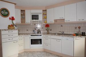 uma cozinha com armários brancos e electrodomésticos brancos em Haus Remler em Matrei in Osttirol
