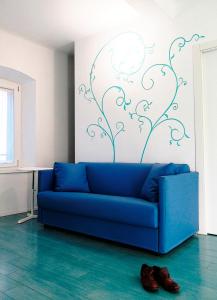 Sofá azul en una habitación con pared en La Corte 20 Studio Apartments, en Carugo