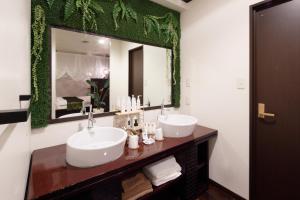 a bathroom with two sinks and a large mirror at Hotel The Lotus Bali (Adult Only) in Kawasaki