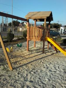 un parque infantil con un banco de madera y un tobogán en Aparthotel Serena, en La Serena