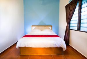 1 dormitorio con 1 cama en una habitación con ventana en SingVillage Holiday House, en Mersing