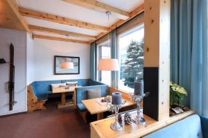 a living room with a blue couch and a table at Hotel Concordia in Davos