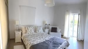a white bedroom with a bed and a chair at SolTroia Glamorous Apartament in Troia +18 photos