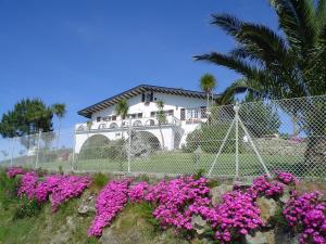 a white house with pink flowers in front of it at Casa A Colina in Porto do Son