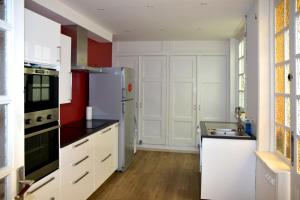 La cuisine est équipée de placards blancs et d'un réfrigérateur blanc. dans l'établissement Chambres d'hôtes L'Escale Malouine, à Dunkerque