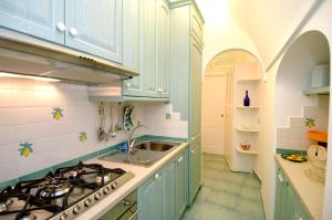 cocina con armarios azules, fregadero y fogones en Quattro Passi, en Amalfi