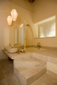 un bagno con tre lavandini e un grande specchio di Castello Camemi a Vizzini